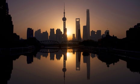 The sun rises behind the skyline of Shanghai in the Lujiazui Financial District of Pudong