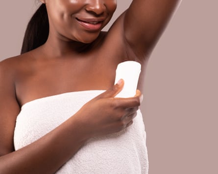 Young black woman using antiperspirant stick under her arms.