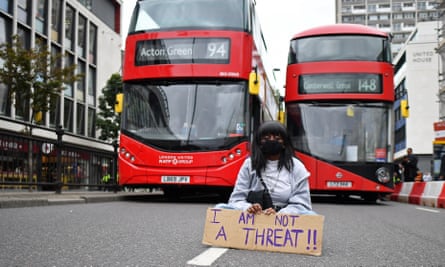 A protester sits in the road blocking the traffic as people gather in Westbourne Park for the inaugural Million People March from Notting Hill to Hyde Park in London on 30 August.