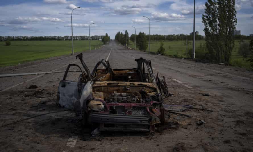 A destroyed vehicle lies in the middle of a road in north Kharkiv.