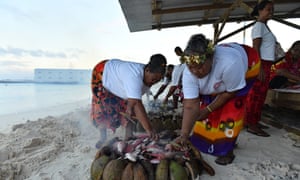 Locals cook fish on an umu, or traditional earth oven, by the lagoon in Funafuti. Groups across the island helped feed the delegates during the foruem.