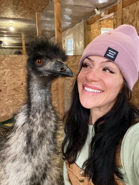 Amanda in a pink woolly hat is eye to eye with an emu