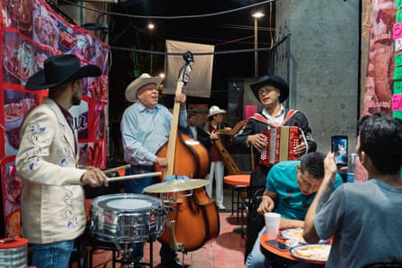 Two young men enjoy a hired mariachi band playing them music while they have a late night dinner. It is the only small restaurant that remains open on Plaza Garibaldi since the pandemic restrictions have come in place.