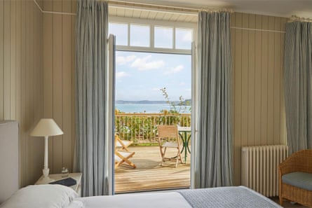 Inside hotel bedroom with open doors on to balcony and sea view