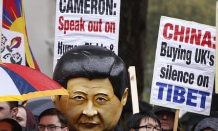 Supporters of Falun Gong, including one wearing a large mask with the likeness of Xi Jinping, protest outside Downing Street.