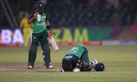 Babar Azam (right) kneels on the pitch after completing his century at Gaddafi Stadium.
