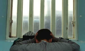 A young inmate looking depressed in a prison cell