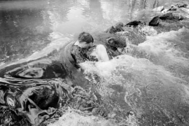 A young man curled up in the rushing river