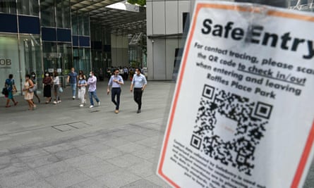 A Covid-19 coronavirus contact tracing sign is pictured as people walk out during lunch break at the Raffles Place financial business district in Singapore on Tuesday.