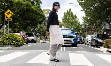 Michael Sun crosses a pedestrian crossing wearing a towel over his trousers