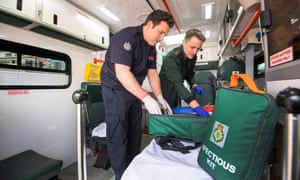 Firefighter Dominic Pearce helps Paramedic Daniel Phillips of the London ambulance service prepare an ambulance for use.