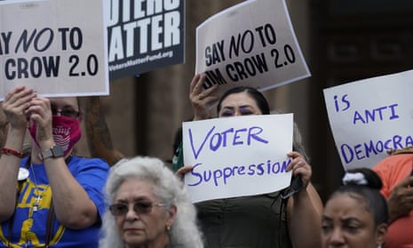 people hold signs saying 'say no to jim crow 2.0' and 'voter suppression is anti-democratic'