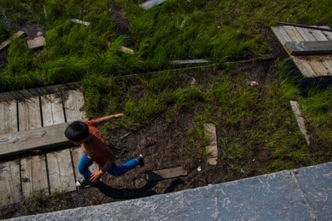 A child jumps over a gap in a boardwalk.