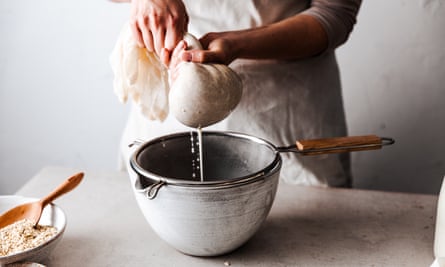 woman straining oats through cloth into bowl