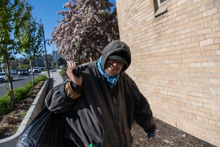 Chris Carver walks to his next destination in downtown Spokane down a tree-lined street by a red-brick building.