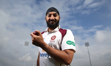 Monty Panesar looks at the camera holding a cricket ball with blue sky behind him