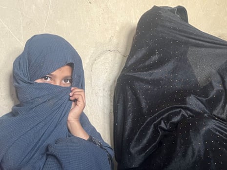 A mother and child with covered faces, in a small hut