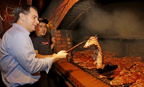 Scott Walker helps Enrique Rivas turn over a slab of ribs at Dreamland BBQ during a campaign stop on Saturday in Birmingham, Alabama.