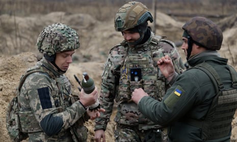 Un grupo de tres soldados con equipo de combate completo hablando.