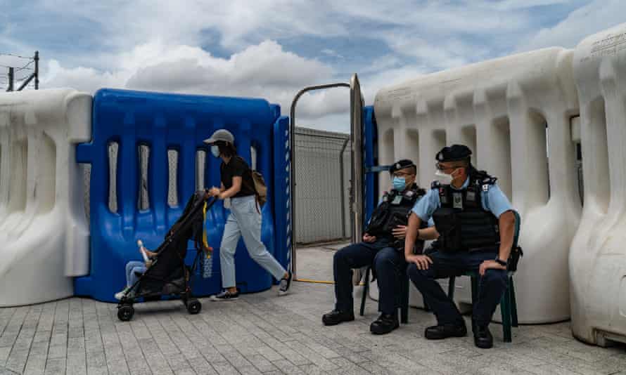 A woman pushing a baby cart walks past police check point outside the West Kowloon High Speed Rail Station ahead of President Xi Jinping’s arrival