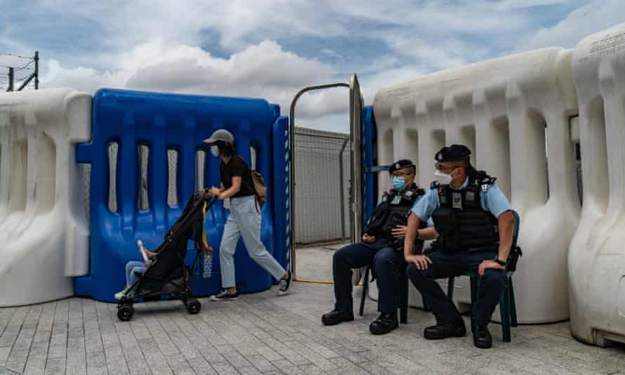 Una mujer que empuja un carrito de bebé pasa por el punto de control de la policía fuera de la estación de tren de alta velocidad de West Kowloon antes de la llegada del presidente Xi Jinping.