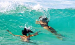 Two women swim under a wave at Bondi Beach, Sydney