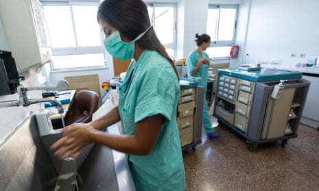Two female medics in surgical scrubs, one washing her hands