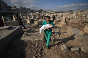 A man carries the body of an infant through a graveyard