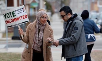 a woman holds a sign that reads "vote uncommitted"