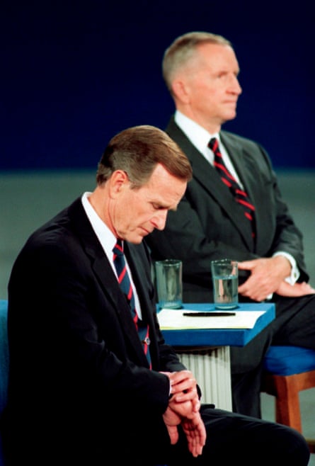 George HW Bush looks at his watch during the 1992 presidential campaign debate with Ross Perot and Bill Clinton.