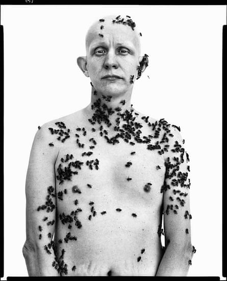 The naked upper torso of a bald man with dozens of bees crawling over him