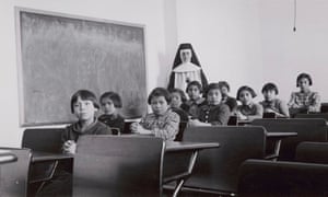 Archive photo of a group of female students and a nun posing in a classroom at Cross Lake Indian Residential School.