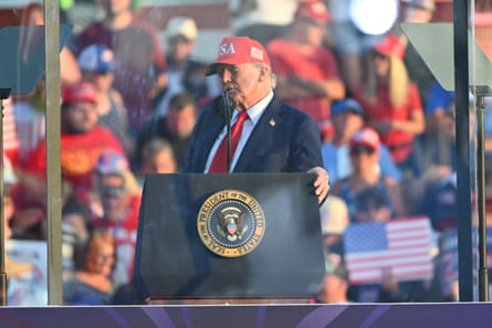 Trump speaks from behind bulletproof glass in Iowa.