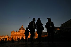 Pedestrians walk past the St Peter’s Basilica of The Vatican, in Rome at twilight