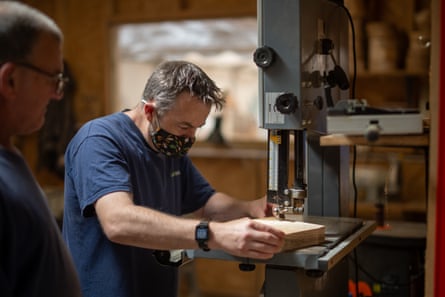 A man using an electric saw on a plank of wood