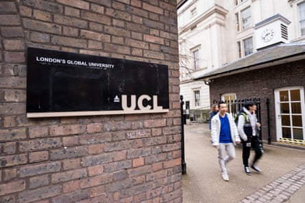 Two young men come out of the main entrance to UCL past a brick wall with a black sign that reads UCL and ‘London’s global university’. They are dressed casually and look as if they could be Chinese or of Chinese origin.