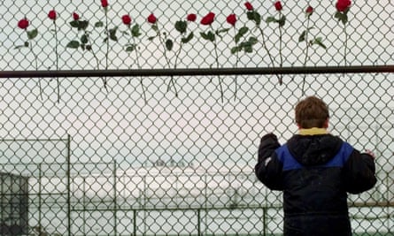 A boy looks through the fence at the Columbine High School tennis courts in Littleton, Colorado on 24 April, 1999. Thirteen roses were placed on the fence in remembrance of those killed by two students at the school.