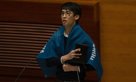 Sixtus Leung, wrapped in a flag that reads ‘Hong Kong is not China’, took his oath with fingers crossed.