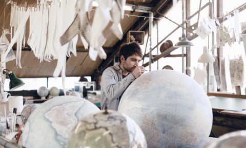 A globe-maker at work on a large globe of the world at Bellerby and Co in north London, UK.