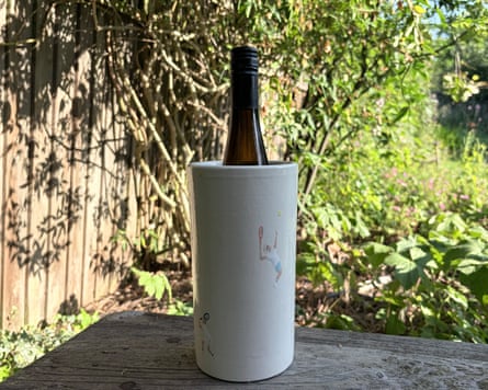 A bottle of wine in Alexandra Browne Wimbledon wine cooler on a garden bench.