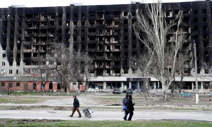 Residents walk past a burned building in the southern Ukrainian port city of Mariupol on 4 April.