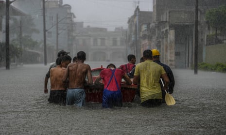 Residents push a boat through a flooded street in Havana