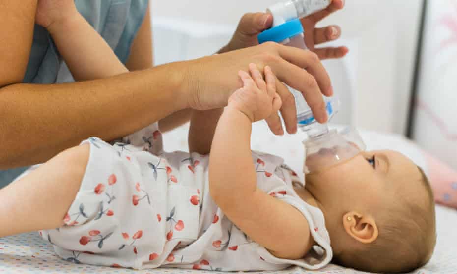 A mother applies an inhaler to her baby.
