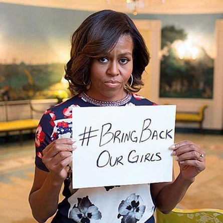 A solemn-looking Michelle Obama holds up a handwritten sign saying #BringBackOurGirls