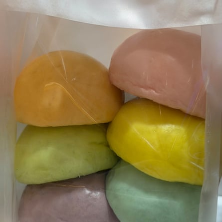Bag with six milk bread rolls in it that have been coloured a variety of different pastel colours