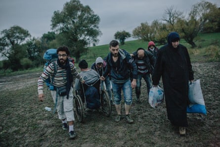 Somar helps a Syrian family move a person in a wheelchair out of a patch of mud after crossing into Serbia from North Macedonia.