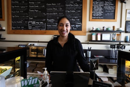 Jemimah Fifita smiles behind a cafe counter with chalkboard menus behind her