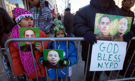 People hold up photographs of NYPD officers Rafael Ramos and Wenjian Liu as the casket of Ramos arrives for his wake.