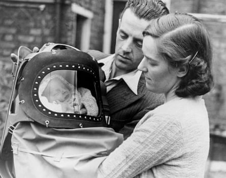 A baby, with his parents, is tried for his gas mask in London just after the declaration of war, 13 September 1939.