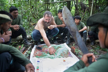 A group of men in the Amazon rainforest study a map.